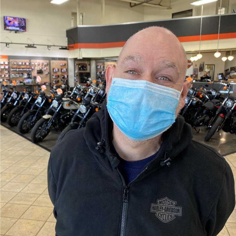 A motorcycle dealership employee on the showroom floor in front of a row of bikes.