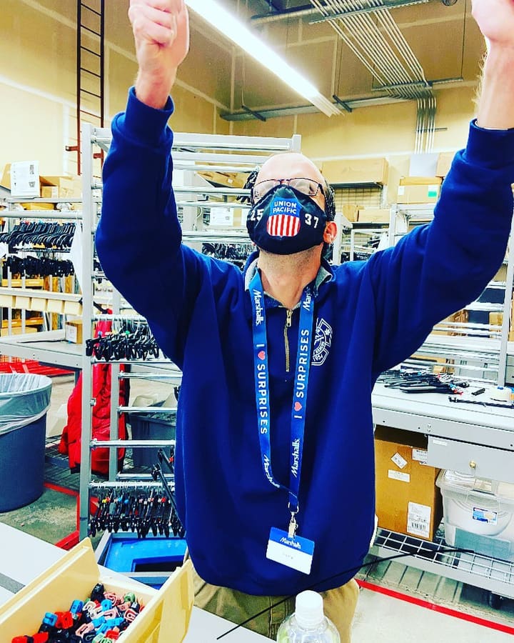 A Marshalls employee raising both arms in celebration in the store's stockroom.